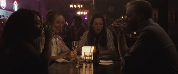 Movie still from “The Night House” (2020), directed by David Bruckner – A group of people sitting at a table with wine glasses; Medium shot, Over the shoulder angle