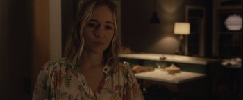 Movie still from “The Night House” (2020), directed by David Bruckner – A woman in a floral shirt is standing in a kitchen; Close Up shot, Over the shoulder angle