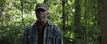 Movie still from “The Night House” (2020), directed by David Bruckner – An older man wearing a hat standing in the woods; Close Up shot, Low angle