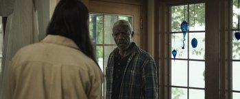 Movie still from “The Night House” (2020), directed by David Bruckner – An older man standing in front of a woman in front of a window; Medium shot, Over the shoulder angle