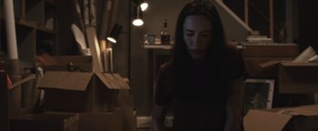 Movie still from “The Night House” (2020), directed by David Bruckner – A woman standing in a dark room with boxes; Medium shot, Low angle