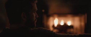 Movie still from “The Night House” (2020), directed by David Bruckner – A man sitting in front of a fire place; Close Up shot, Over the shoulder angle