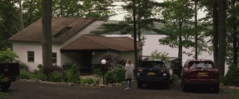 Movie still from “The Night House” (2020), directed by David Bruckner – A woman standing in front of a house next to a car; Extreme Wide shot, High angle