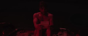 Movie still from “The Night House” (2020), directed by David Bruckner – A man sitting on the ground holding a piece of paper; Medium shot, Low angle