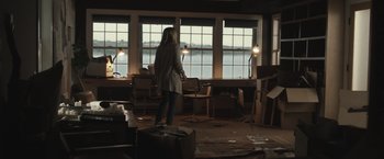 Movie still from “The Night House” (2020), directed by David Bruckner – A person standing in a room with a lot of boxes; Wide shot, Over the shoulder angle