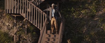 Movie still from “The Night House” (2020), directed by David Bruckner – An older man is walking up the stairs; Wide shot, High angle