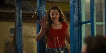 Movie still from “The Nightingale of Bursa” (2023), directed by Hakan Algül – A woman in a red shirt is waving to the camera; Medium shot, Over the shoulder angle