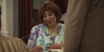Movie still from “The Nightingale of Bursa” (2023), directed by Hakan Algül – An older woman sitting at a table with a piece of paper; Close Up shot, Over the shoulder angle