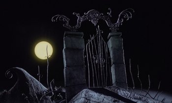 Movie still from “The Nightmare Before Christmas” (1993), directed by Henry Selick – A full moon rises behind a gate and fence; Wide shot, Low angle