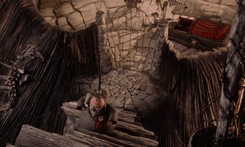 Movie still from “The Nightmare Before Christmas” (1993), directed by Henry Selick – An image of a man standing on a wooden platform in the middle of a cave; Wide shot, Overhead angle