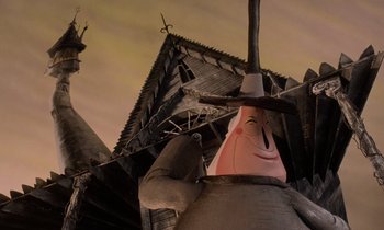 Movie still from “The Nightmare Before Christmas” (1993), directed by Henry Selick – A statue of a man with a hat on; Wide shot, Low angle