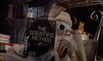 Movie still from “The Nightmare Before Christmas” (1993), directed by Henry Selick – A skeleton holding a book in front of a fireplace; Medium shot, High angle