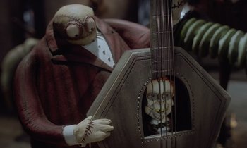 Movie still from “The Nightmare Before Christmas” (1993), directed by Henry Selick – A person with a guitar and a puppet; Medium shot, High angle