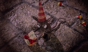Movie still from “The Nightmare Before Christmas” (1993), directed by Henry Selick – A rat wearing a party hat eating a piece of cake; Extreme Close Up shot, High angle