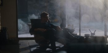 Movie still from “The Noel Diary” (2022), directed by Charles Shyer – A man sitting in a chair in front of a window; Wide shot, Low angle
