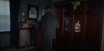 Movie still from “The Noel Diary” (2022), directed by Charles Shyer – A man in a suit holding a basketball in a room; Wide shot, Over the shoulder angle