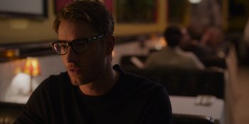 Movie still from “The Noel Diary” (2022), directed by Charles Shyer – A man with glasses is sitting in a room; Close Up shot, Over the shoulder angle
