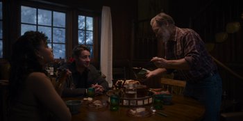 Movie still from “The Noel Diary” (2022), directed by Charles Shyer – A group of people sitting at a table with food; Medium shot, Over the shoulder angle