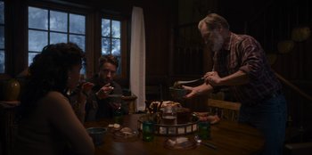 Movie still from “The Noel Diary” (2022), directed by Charles Shyer – A group of people sitting around a table eating food; Medium shot, Low angle