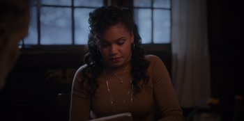 Movie still from “The Noel Diary” (2022), directed by Charles Shyer – A woman sitting at a table looking down at a book; Close Up shot, High angle