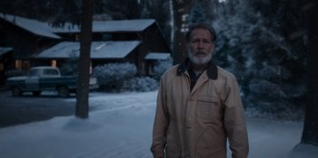 Movie still from “The Noel Diary” (2022), directed by Charles Shyer – An older man standing in front of a cabin in the snow; Medium shot, Over the shoulder angle