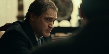 Movie still from “Dopesick” (2021), directed by Danny Strong – A person wearing a suit and tie; Close Up shot, Over the shoulder angle