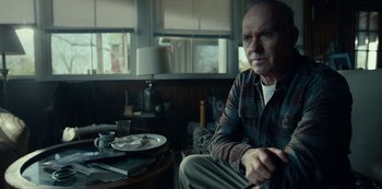 Movie still from “Dopesick” (2021), directed by Danny Strong – An older man sitting at a table in a living room; Medium shot, Over the shoulder angle