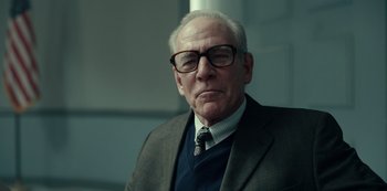 Movie still from “Dopesick” (2021), directed by Danny Strong – An older man wearing glasses and a suit; Close Up shot, Low angle