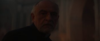 Movie still from “The Nun II” (2023), directed by Michael Chaves – An old man with a beard is looking at the camera; Close Up shot, Over the shoulder angle