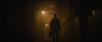 Movie still from “The Nun II” (2023), directed by Michael Chaves – A man holding a briefcase walking down a dark hallway; Wide shot, Low angle