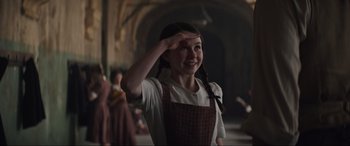 Movie still from “The Nun II” (2023), directed by Michael Chaves – A young girl in an apron is holding her hand up to her head; Medium shot, Low angle