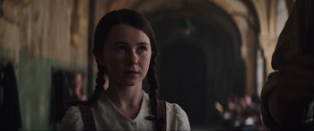 Movie still from “The Nun II” (2023), directed by Michael Chaves – A young girl with pigtails standing in front of a building; Close Up shot, Low angle