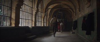 Movie still from “The Nun II” (2023), directed by Michael Chaves – A man walking down a hall way with people in the background; Wide shot, Low angle