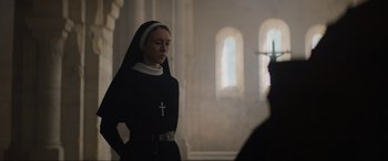 Movie still from “The Nun II” (2023), directed by Michael Chaves – A woman in a nun's outfit standing in front of a window; Medium shot, Low angle