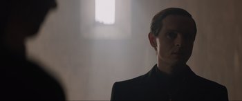 Movie still from “The Nun II” (2023), directed by Michael Chaves – A man in a black suit standing in front of a window; Close Up shot, Low angle