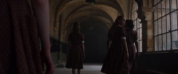 Movie still from “The Nun II” (2023), directed by Michael Chaves – Two women in dresses are walking in a dark room; Wide shot, Low angle