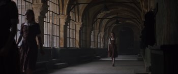 Movie still from “The Nun II” (2023), directed by Michael Chaves – A woman walking in an old looking building; Wide shot, Low angle