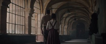 Movie still from “The Nun II” (2023), directed by Michael Chaves – A man and a woman are walking in a hallway; Wide shot, Low angle