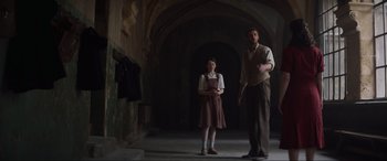 Movie still from “The Nun II” (2023), directed by Michael Chaves – A man and a woman standing next to each other in an archway; Wide shot, Low angle