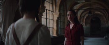 Movie still from “The Nun II” (2023), directed by Michael Chaves – A woman in a red dress standing next to a window; Medium shot, Over the shoulder angle