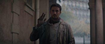 Movie still from “The Nun II” (2023), directed by Michael Chaves – A man in a trench coat holding up three fingers; Medium shot, Low angle