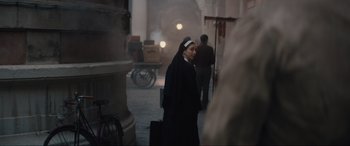 Movie still from “The Nun II” (2023), directed by Michael Chaves – A nun walking down the street with a suitcase in her hand; Medium shot, Over the shoulder angle