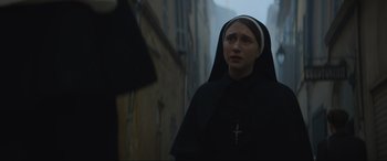 Movie still from “The Nun II” (2023), directed by Michael Chaves – A woman wearing a nun's habit and a cross on her head; Close Up shot, Low angle