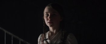 Movie still from “The Nun II” (2023), directed by Michael Chaves – A young girl in a white shirt and pigtails; Close Up shot, Low angle