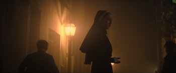 Movie still from “The Nun II” (2023), directed by Michael Chaves – A woman in a nun's habit standing in a dimly - lit room; Medium shot, Low angle