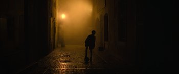 Movie still from “The Nun II” (2023), directed by Michael Chaves – A person standing on a street with a soccer ball; Wide shot, Low angle