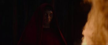 Movie still from “The Nun II” (2023), directed by Michael Chaves – A man in a red robe standing in a dark room; Close Up shot, Low angle