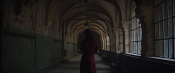 Movie still from “The Nun II” (2023), directed by Michael Chaves – A woman in a red dress walking down a hallway; Wide shot, Over the shoulder angle