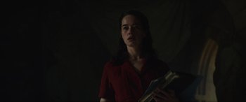 Movie still from “The Nun II” (2023), directed by Michael Chaves – A woman in a red shirt is holding a book; Medium shot, Low angle