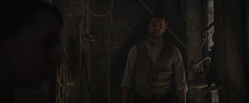 Movie still from “The Nun II” (2023), directed by Michael Chaves – A man standing in front of a wall with ropes; Medium shot, Low angle